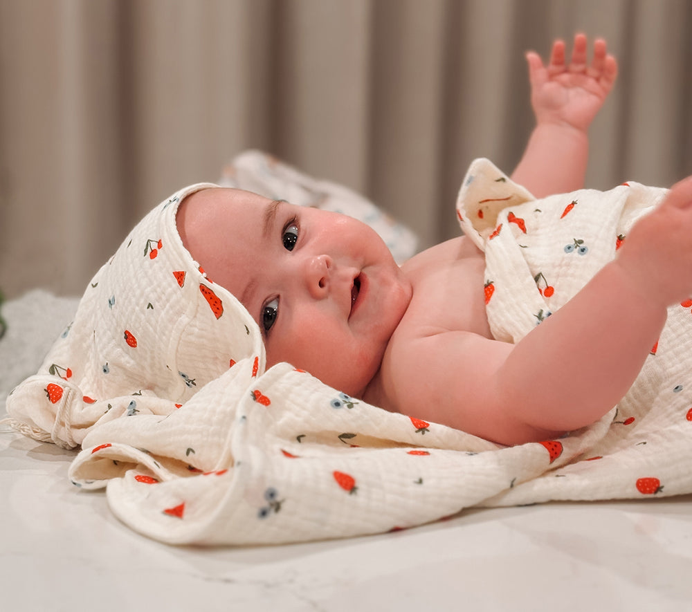 Baby wrapped in hooded towel with sweet pickings fruit print 