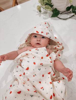 Baby wrapped in hooded bath towel with sweet pickings fruit pattern