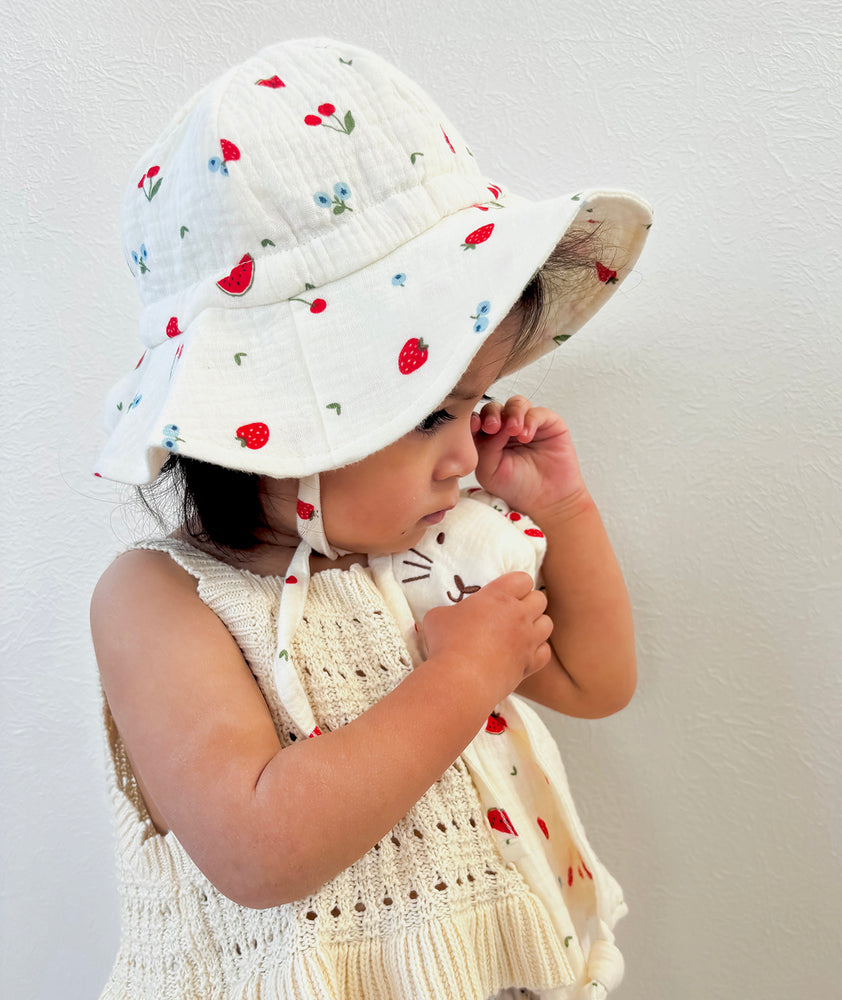 Toddler wearing sun hat with watermelon and strawberry print 