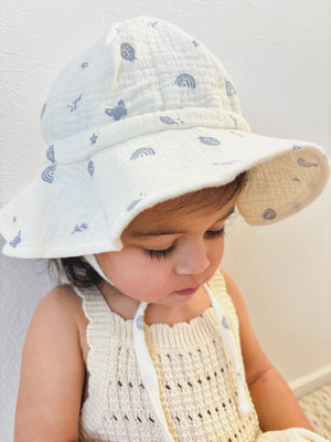 Toddler wearing muslin sun hat with enchanted garden print in blue 